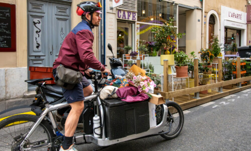 Marseille, France March 13, 2025 A bicyclist carries flowers from a florist on Rue Sainte in Le Vieux Port, or Old Port, district.